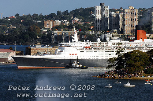 While Queen Victoria slips out of Circular Quay, Queen Elizabeth II with tugs slips out of Woolloomooloo Bay.