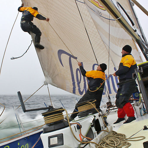 Straight into cold and windy conditions. Daryl Wislang is adding a new sheet to the jib and is holding onto it while Xabier Fernandez is pulling him towards the boat, during leg 7 from Boston to Galway.