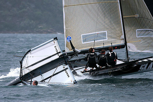 Western Australia’s SLAM skippered by Grant Rollerson passes by a capsised Moth, during Race 12 of the Club Championship Race. Photo copyright Australian 18 Footers League.