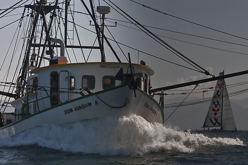 Torben Grael's S40 Mitsubishi - GOL (Magia V) (BRA) behind a local fishing trawler, during the Rolex Ilhabela Sailing Week 2010. Photo copyright Rolex and Carlo Borlenghi.